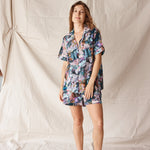 Woman wearing floral pyjamas standing against a plain background