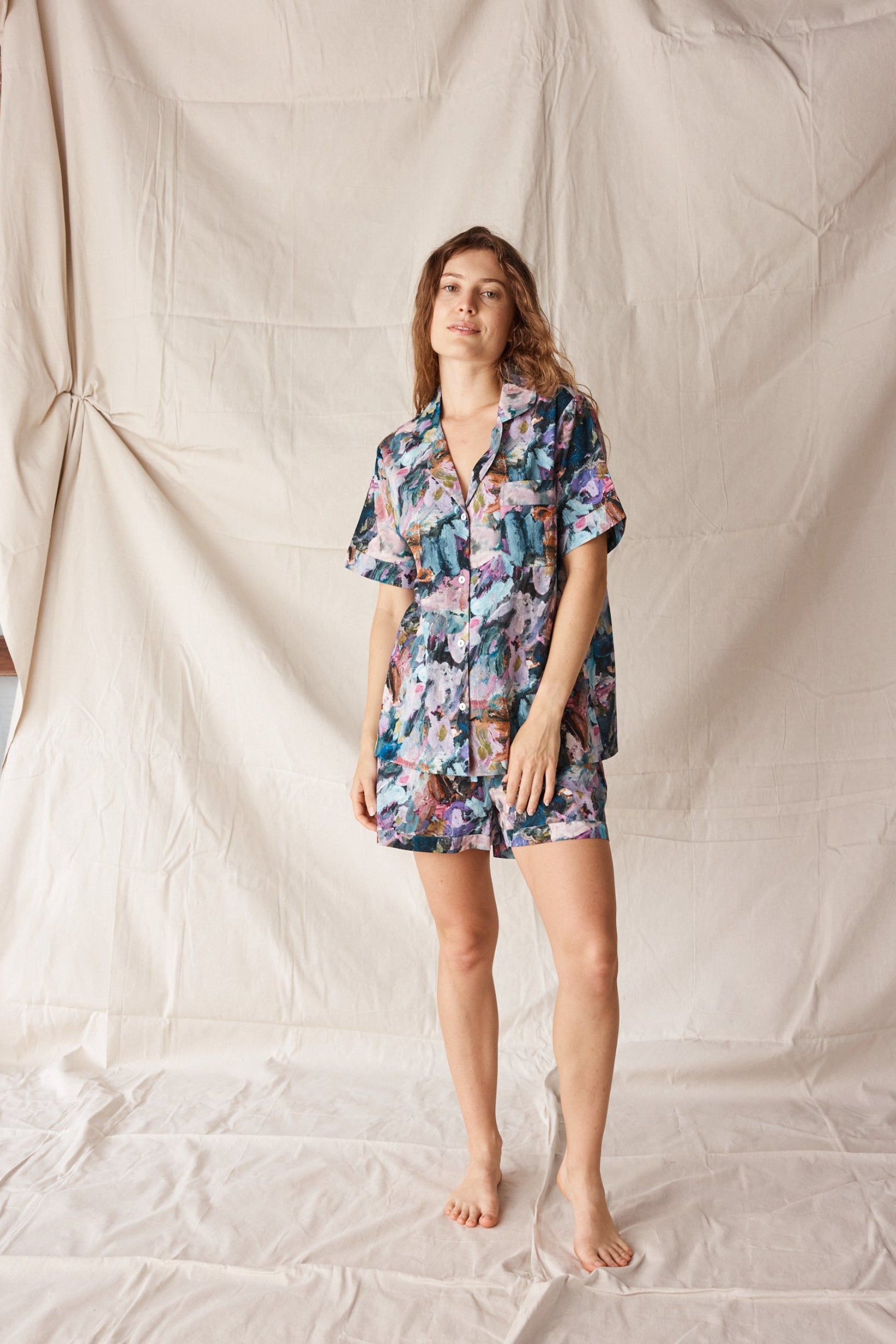 Woman wearing floral pyjamas standing against a plain background