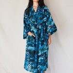 Woman wearing a blue floral patterned robe against a white background