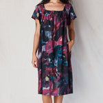 Woman wearing a colorful dress against a plain background