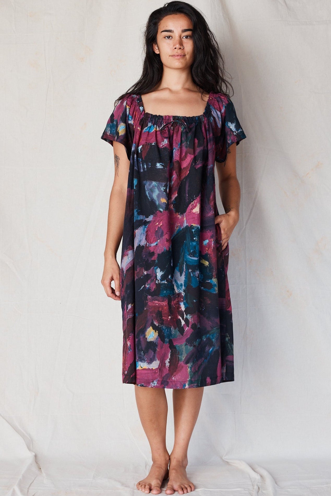 Woman wearing a colorful dress against a plain background